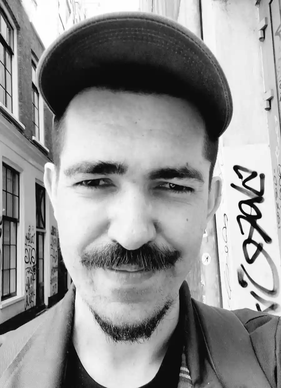 The author, Heydon, standing in an Amsterdam street, in the sun, wearing a baseball cap